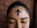 Ash cross on woman's forehead representing Ash Wednesday