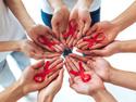 A group of hands holding a red AIDS band